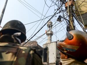 Security personnel stand guard on a road as an Indian national flag is seen on a minaret (C) of a burnt-out mosque following clashes between people supporting and opposing a contentious amendment to India's citizenship law in New Delhi on February 26, 2020. AFP