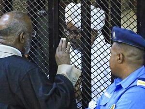 Sudan's deposed president Omar al-Bashir sits in a defendant's cage during his corruption trial at a court in Khartoum on December 14, 2019. (AFP)