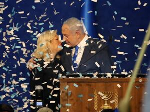Israeli Prime Minister Benjamin Netanyahu approaches to kiss his wife Sara as confetti falls upon them while addressing supporters at the Likud party campaign headquarters in the coastal city of Tel Aviv early on March 3, 2020, after polls officially closed. Netanyahu claimed "a giant victory" in elections on March 3, boasting that his right-wing Likud party had defied "all expectations" in the country's third vote in less than a year. After exit polls by three networks forecast that Likud and its allies we