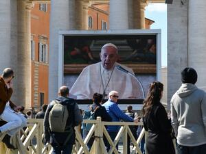 People watch a screen live-broadcasting Pope Francis' Sunday Angelus prayer on St. Peter's Square at the Vatican on March 8, 2020, after millions of people were placed under forced quarantine in northern Italy as the government approved drastic measures in an attempt to halt the spread of the COVID-19 outbreak, caused by the novel coronavirus that is sweeping the globe. On top of the forced quarantine of 15 million people in vast areas of northern Italy until April 3, the government has also closed schools,