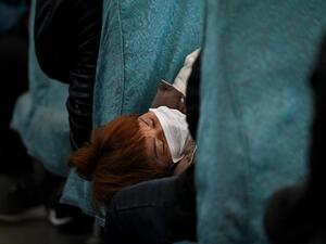 A passenger wearing a face mask naps inside a train as it passes through Wuhu in China's southeastern Anhui province on March 13, 2020. China reported just eight cases of the covid-19 coronavirus outbreak on March 13, with no new domestic infections outside the epicentre of Hubei province. Noel Celis / AFP