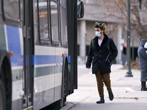 A man in a mask boards a bus on campus at Western University in London, Ontario on March 13, 2020 where in person classes have been suspended for the rest of the school year in favour of online instruction due to concerns over the the novel coronavirus, COVID-19. Geoff Robins / AFP