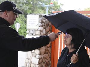 An Israeli security guard measures the temperature of a woman at the entrance to a retirement home in the Ramat Efal district of Ramat Gan in Israel, on March 17, 2020. JACK GUEZ / AFP