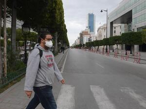 A man wearing a face mask crosses a street at Habib Bourguiba Avenue in Tunis on March 18, 2020 shortly before a night curfew imposed to halt the spread of coronavirus. Tunisia has reported 24 coronavirus cases and while no deaths have been reported in the country, the virus has killed more than 6,000 worldwide. FETHI BELAID / AFP