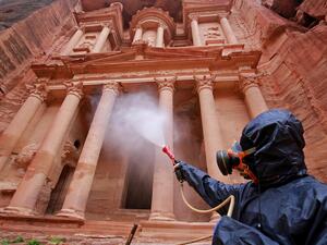 A labourer sprays disinfectant in Jordan's archaeological city of Petra south of the capital Amman on 17 March, to prevent the spread of Covid-19 (AFP)
