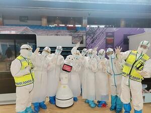A group of medical workers are pictured with one of the robots in Wuchang field hospital (Dailymail)