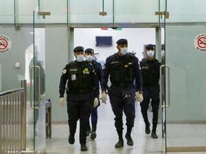 Kuwaiti policemen wearing protective masks wait at Sheikh Saad Airport in Kuwait City, on February 22, 2020, before transferring Kuwaitis arriving from Iran to a hospital to be tested for coronavirus. (File photo: AFP)
