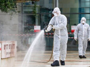 An Israeli firefighter sprays disinfectant at the entrance of Ichilov Hospital in Tel Aviv on March 20, 2020. (Jack Guez/AFP)