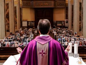 Don Giuseppe Corbari, parson of the Church of Robbiano, holds Sunday mass as he looks towards selfie photographs sent in by his congregation members and glued to empty pews in Giussano on March 22, 2020. AFP
