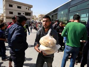 People queue to buy subsidised bread from a municipal bus in the Marka suburb in the east of Jordan's capital Amman on March 24, 2020, as the kingdom announced it would deliver bread and water supplies after the government decided to indefinitely extend a curfew amidst efforts to contain COVID-19 coronavirus disease. Jordan imposed a curfew after citizens failed to heed instructions not to leave home except for emergencies, and it has deployed the army to enforce the measure. A fleet of 190 buses chartered 