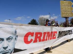 An anti-incumbent government protester waves an Israeli flag tainted in black in front of banner showing Israeli Prime Minister Benjamin Netanyahu, during a demonstration in front of the Knesset celebrating the resignation of the Knesset Speaker in Jerusalem on March 25, 2020. Yuli Eldenstein, th speaker of Israel's parliament, an ally of Prime Minister Benjamin Netanyahu, resigned, clearing the way for a vote that could see him replaced by an opponent of the embattled premier. Emmanuel DUNAND / AFP
