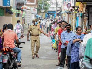 A policeman (C) patrols as people queue to receive free rice distributed at a government civil supply store during a government-imposed nationwide lockdown as a preventive measure against the COVID-19 coronavirus, in Hyderabad on April 1, 2020. NOAH SEELAM / AFP