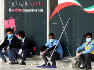 Cleaners wearing facemasks rest at the Kuwait International Airport Terminal 4, on April 3, 2020 amid the coronavirus COVID-19 pandemic crisis. YASSER AL-ZAYYAT / AFP
