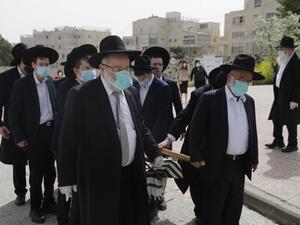 Pallbearers from the Ultra-Orthodox Jewish burial society (Hevrat kadishah), wearing surgical masks as a precaution against COVID-19 coronavirus disease, carry the coffin of an elderly man (not a COVID-19 victim) during a funeral outside the Shamgar funeral house in Jerusalem on April 5, 2020. MENAHEM KAHANA / AFP