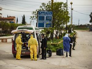 Members of the Kurdish Red Crescent check passengers who were stranded in Damascus upon their arrival at the Qamishli airport in Syria's northeastern Hasakeh province on April 5, 2020. Passengers will undergo a two-week quarantine at a designated centre in the Kurdish-majority city of Qamishli. DELIL SOULEIMAN / AFP