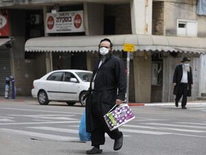 An ultra-Orthodox Jewish man wearing a protective mask, walks by carrying bags of shopping in the religious Israeli city of Bnei Brak, near Tel Aviv, on April 06, 2020 during the novel coronavirus pandemic crisis. More than 7,000 cases of COVID-19, including 40 deaths, have been officially declared in Israel, half of which according to local media, are ultra-Orthodox Jews, prompting the Prime Minister on April 3, to give a green light for amry deployment in the city, considered the centre of the country's n