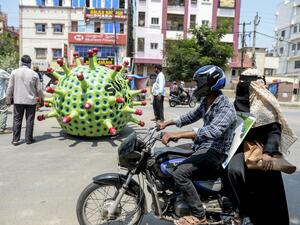 People drive past as inventor Sudhakar Yadav (inside) leads his coronavirus-themed made car on a road for an awareness campaign during a government-imposed nationwide lockdown as a preventive measure against the COVID-19 coronavirus, in Hyderabad on April 8, 2020. NOAH SEELAM / AFP