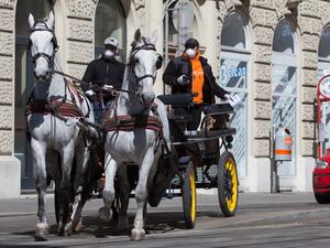 A horse-drawn carriage turns at an intersection in the 3rd district in Vienna, Austria on April 8, 2020. The Hotel Intercontinental cooks up to 350 lunches a day for people in need who are unable to feed themselves due to the coronavirus pandemic. The meals are delivered voluntarily by fiaker drivers. ALEX HALADA / AFP