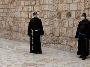 Franciscan friars wearing protective masks amid the COVID-19 pandemic stand in the yard of the Church of the Holy Sepulchre in Jerusalem's Old City, on April 9, 2020. All cultural sites in the Holy Land are shuttered, regardless of their religious affiliation, as authorities seek to forestall the spread of the deadly respiratory disease, which will prevent Christians from congregating for the Easter service, this coming Sunday for Catholic worshippers, then a week later on April 19 for Orthodox Easter. GALI