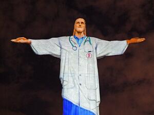 View of the world famous Christ the Redeemer statue on Easter day with a doctor's uniform projected on it in honour of all the medical staff fighting the COVID-9 coronavirus pandemic worldwide in Rio de Janeiro, Brazil on April 12, 2020. CARL DE SOUZA / AFP