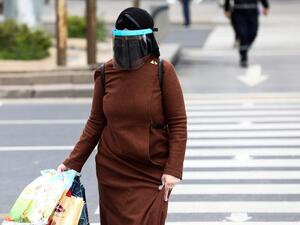 A woman wearing a face-shield and plastic gloves for protective measures crosses the streets as the spread of the COVID-19, the novel coronavirus continues in Ankara, on April 16, 2020. Adem ALTAN / AFP