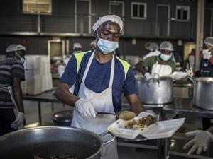 A volunteer pours a ladle of food into a container as he prepares packed relief meals at the Meals on Wheels Community Services South Africa in Johannesburg, on April 21, 2020. AFP