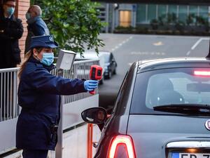 A security agent (L) scans the body temperature of an employee of Italian automobile manufacturer Fiat arriving by car at the Mirafiori plant in Turin, as work resumes on April 27, 2020 after the government laid out partial reopening plans. (AFP)