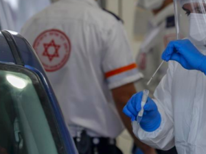 A paramedic with Israel's Magen David Adom medical service tests a man for COVID-19 at a drive-through site in Jabal Mukaber [Ahmad Gharabli/AFP]