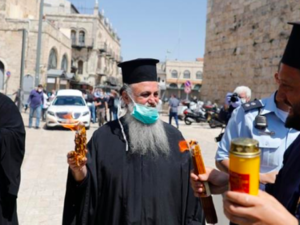 Greek Orthodox priests hold candles lit from the Holy Fire in the church of the Holy Sepulchre [Ahmad Gharabli/AFP]