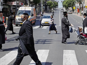 Ultra-Orthodox Jews, some of them wearing masks, cross a street in the religious Israeli city of Bnei Brak, near Tel Aviv, on March 3, 2020 during the novel coronavirus pandemic crisis. (AFP)
