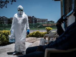A laboratory specialist wearing protective gear speaks with a man asking to get tested in front of the ward for quarantined people who had close contacts with the first Kenyan patient of the COVID-19 at the Infectious Disease Unit of Kenyatta National Hospital in Nairobi, Kenya, on March 15, 2020. (AFP/File Photo)
