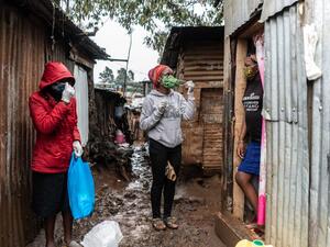 Florence Akiuor (2nd L) of Coalition for grassroots human rights defenders Kenya (CGHRD'S Kenya) explains how to use a mask during their food distribution. (AFP)