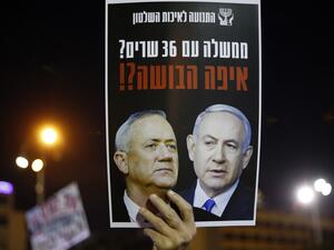 A protester carries a placard with a picture of Prime Minister Benjamin Netanyahu (R) and his rival-turned-partner Benny Gantz, during a demonstration in Tel Aviv's Rabin Square on May 2, 2020, in favour of the Supreme Court to consider tomorrow to block the coalition government agreed between the two men. If the expanded panel of 11 judges set to hear the case deems the coalition deal invalid, Israel may be forced to hold its fourth election in less than two years. JACK GUEZ / AFP