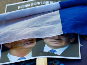 A rolled Israeli flag lies upon a placard left on the street with a picture of Prime Minister Benjamin Netanyahu and his rival-turned-partner Benny Gantz, during a demonstration in Tel Aviv's Rabin Square on May 2, 2020, in favour of the Supreme Court to consider tomorrow to block the coalition government agreed between the two men. If the expanded panel of 11 judges set to hear the case deems the coalition deal invalid, Israel may be forced to hold its fourth election in less than two years. JACK GUEZ / AF