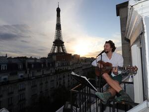 Singer Adrien Pelon aka "Adri1" performs from his balcony for his neighborhood on May 2, 2020, in Paris, as the country is under lockdown to stop the spread of the Covid-19 pandemic caused by the novel coronavirus. Ludovic MARIN / AFP