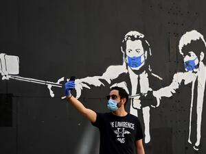 A man takes a selfie photo in front of a stencil graffiti depicting US actors John Travolta and Samuel L. Jackson in their roles of "Vincent Vega" and "Jules Winnfield" in Quentin Tarantino's "Pulp Fiction", wearing face masks, in Madrid on May 3, 2020 amid a national lockdown to prevent the spread of the COVID-19 disease. Spain today counted another 164 coronavirus deaths, the lowest daily number in nearly seven weeks as the country begins to gradually lift its strict lockdown. The figures from the health 