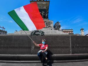 A woman waves the Italian flag on May 4, 2020 in Milan as Italy starts to ease its lockdown, during the country's lockdown aimed at curbing the spread of the COVID-19 infection, caused by the novel coronavirus. AFP/File