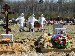 Cemetery workers wearing protective gear bury a coronavirus victim at a cemetery on the outskirts of Saint Petersburg on May 6, 2020. OLGA MALTSEVA / AFP