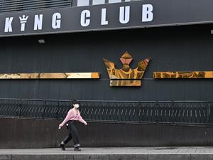 A woman wearing a face mask walks past a night club, now closed following a visit by a confirmed COVID-19 coronavirus coronavirus patient, in the popular nightlife district of Itaewon in Seoul on May 10, 2020. South Korea's capital has ordered the closure of all clubs and bars after a burst of new cases sparked fears of a second coronavirus wave as President Moon Jae-in urged the public to remain vigilant. Jung Yeon-je / AFP