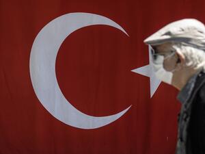 An elderly man wearing a protective face mask, walks past the Turkish flag on May 10, 2020, at Besiktas in Istanbul, after a month and a half of lockdown restrictions aimed at stemming the spread of the novel coronavirus, COVID-19. Turkish people aged 65 and over on May 10, 2020, described their joy after the government allowed them to go outside for the first time in nearly two months in an easing of the coronavirus restrictions. While 24 provinces including Ankara and Istanbul are subject to a weekend loc