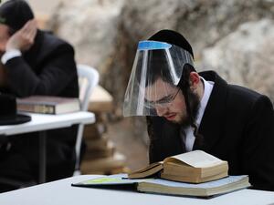 Ultra-Orthodox Jews wearing protective gear and observing social distancing amid the COVID-19 pandemic, study the Talmud and rabbinic literature at an improvised outdoors Kollel (gathering place for religious studies) at a park in their Ultra-orthodox neighbourhood in Jerusalem, on May 11, 2020. MENAHEM KAHANA / AFP