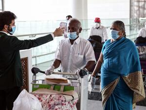 Indian nationals residing in Oman, wearing face masks due to the COVID-19 coronavirus pandemic, have their body temperatures measured at a terminal in Muscat International Airport ahead of their repatriation flight from the Omani capital, on May 12, 2020. MOHAMMED MAHJOUB / AFP