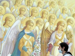 A man wearing a face mask walks in front of frescos of Mykhaylo Gold Domes cathedral in the center of the Ukrainian capital of Kiev on May 12, 2020, after Ukraine started to ease anti-virus restrictions imposed to curb the spread of the COVID-19 outbreak, caused by the novel coronavirus. Sergei SUPINSKY / AFP