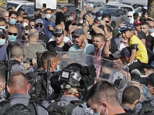 People chant slogans as they gather before Israeli security forces for a demonstration near the northern Arab Israeli city of Arara on May 14, 2020, after a man was shot to death after stabbing a security guard outside Tel Hashomer Hospital. Ahmad GHARABLI / AFP