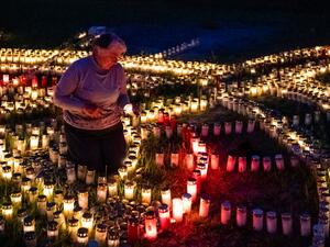 60-year-old Gertrud Schop lights candles arranged in the shape of a cross, with one candle dedicated to each of the more than 8,000 German Covid-19-related victims, in Zella-Mehlis, eastern Germany on May 19, 2020, amid the novel coronavirus / COVID-19 pandemic. Schop is planning to continue the project until a vaccine against Covid-19 is available. JENS SCHLUETER / AFP