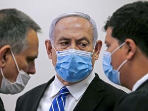 Israeli Prime Minister Benjamin Netanyahu (C), wearing a protective face maks, speaks with his lawyer inside a courtroom at the district court of Jerusalem on May 24, 2020, during the first day of his corruption trial. RONEN ZVULUN / POOL / AFP