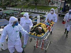 Health personnel of a medical emergency response service carry Brazilian Eladio Lopes, 79, -infected with the new coronavirus- on a stretcher to be transferred on an ambulance boat from the community of Portel to a hospital in Breves, on Marajo island, Para state, Brazil, on May 25, 2020. Ambulance boat services allow critical COVID-19 patients to be tranferred in very remote areas surrounded by water in Brazil. TARSO SARRAF / AFP
