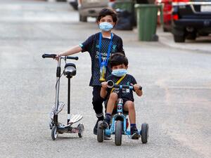 Kuwaiti children, wearing protective facemasks due to the coronavirus pandemic, cycle in a street in the Salwa district of Kuwait City on May 29, 2020. YASSER AL-ZAYYAT / AFP