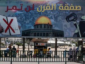 The picture taken on June 16, 2019, shows a poster in Gaza City denouncing US President Donald Trump's so-called peace plan, reading, "The deal of the century will not pass." (By AFP)