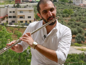 Ebaa Akroush, a 24-year-old Jordanian music graduate from the University of Jordan and first-prize winner of a culture ministry talent contest, plays the flute on his balcony in Fuheis town, around 20 kilometres northwest of the capital Amman, on April 27, 2020. (Photo by Khalil MAZRAAWI / AFP)